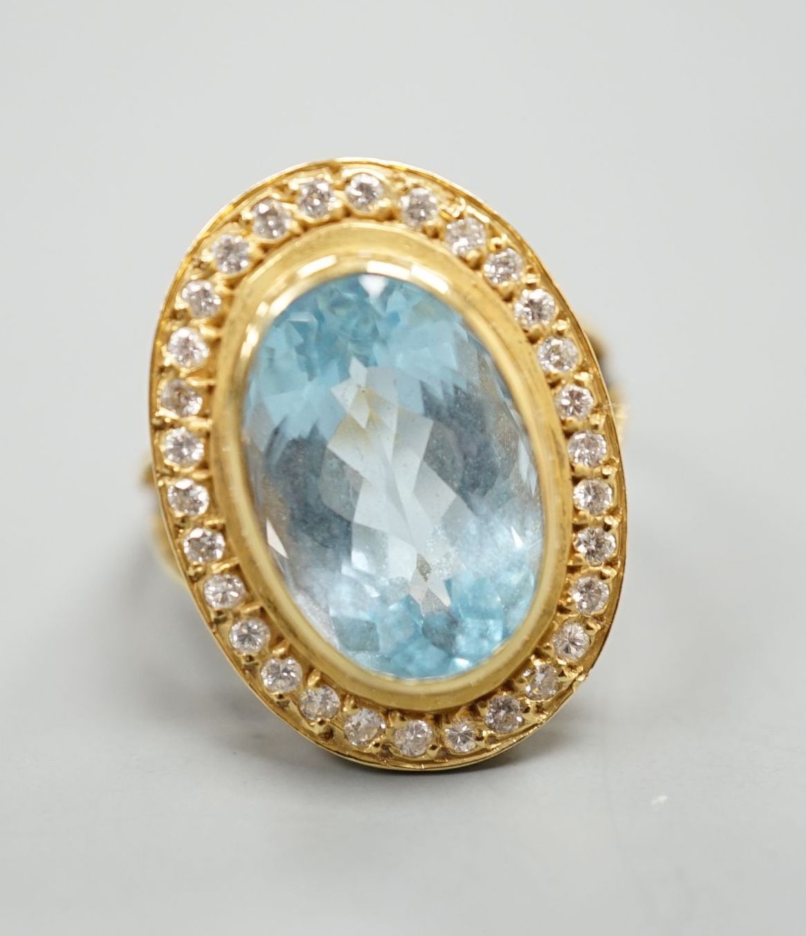 A modern 18ct gold, blue topaz and diamond set oval cluster ring, size L/M, gross weight 8.3 grams.
